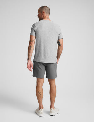 Man wearing a gray t-shirt and shorts on a white background. 