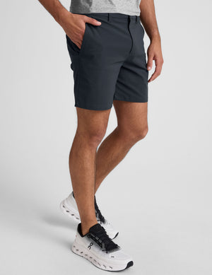 man wearing a gray crew neck t-shirt and blue chino shorts with pockets on a plain background. 