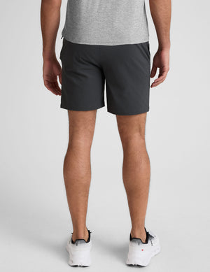 man wearing a gray crew neck t-shirt and blue chino shorts with pockets on a plain background. 