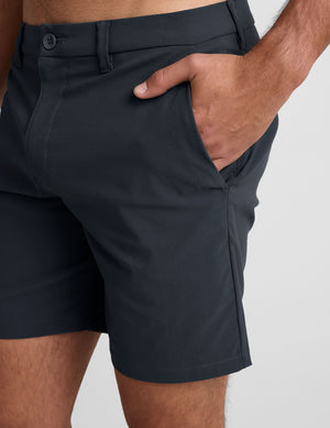 man wearing a gray crew neck t-shirt and blue chino shorts with pockets on a plain background. 