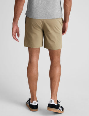 man wearing a grey crew neck t-shirt and beige chino shorts with pockets standing against a plain background. 