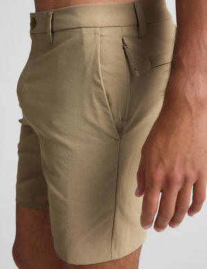 man wearing a black hoodie and beige chino shorts with pockets standing against a plain background. 