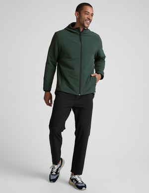 man wearing a green jacket with a hood on a gray background. 