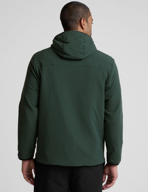 man wearing a green jacket with a hood on a gray background. 