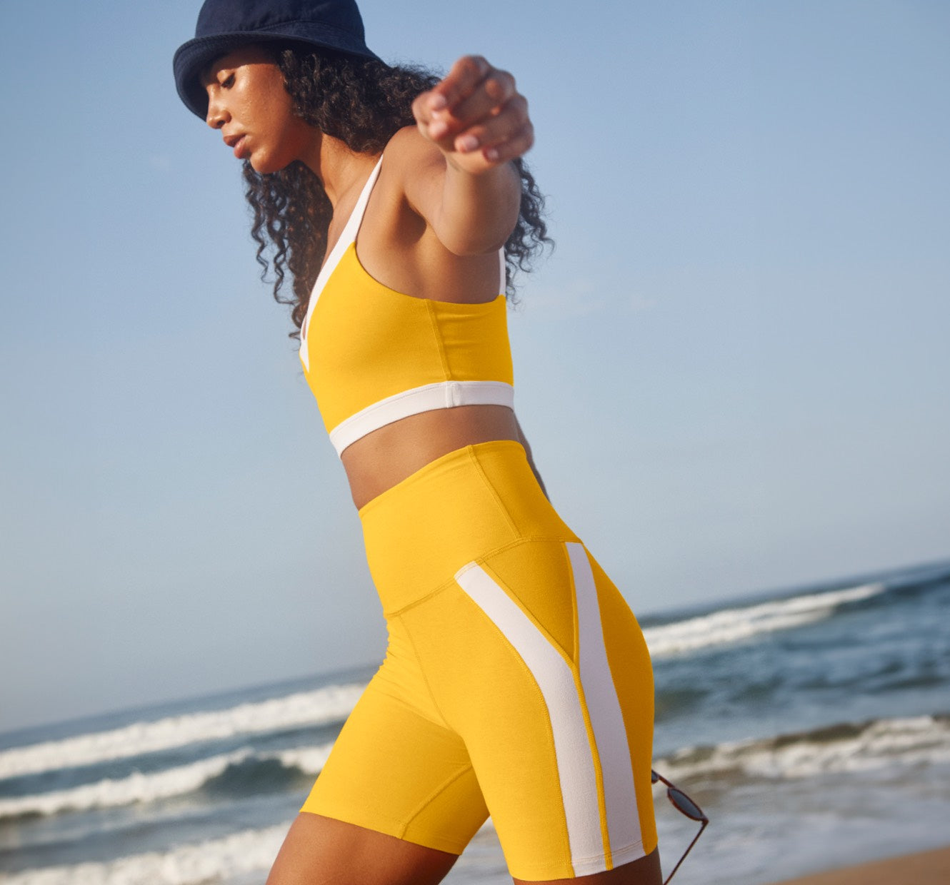 model is wearing a yellow bra top with white outline details and yellow high-waisted biker shorts with white outline detailing. 