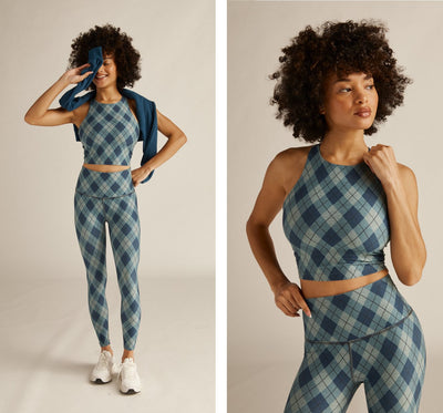 model is wearing a blue argyle printed high-neck racerback crop tank and blue argyle printed high-waisted midi leggings. 