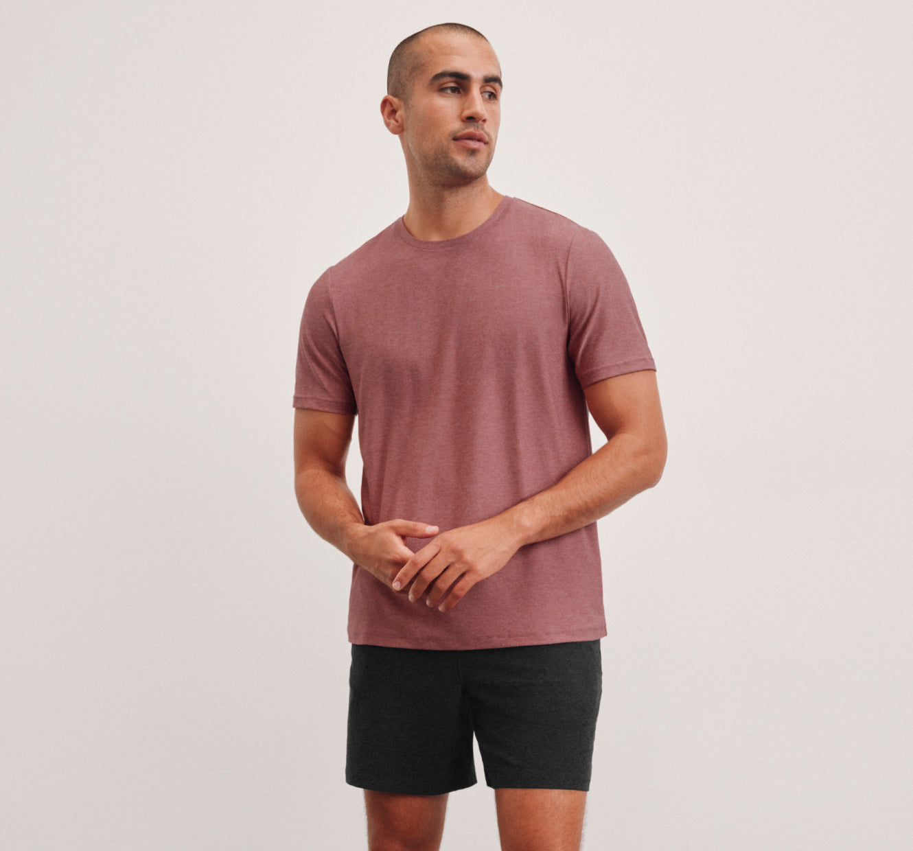 model is wearing a red men's lightweight short sleeve shirt and black men's shorts. 