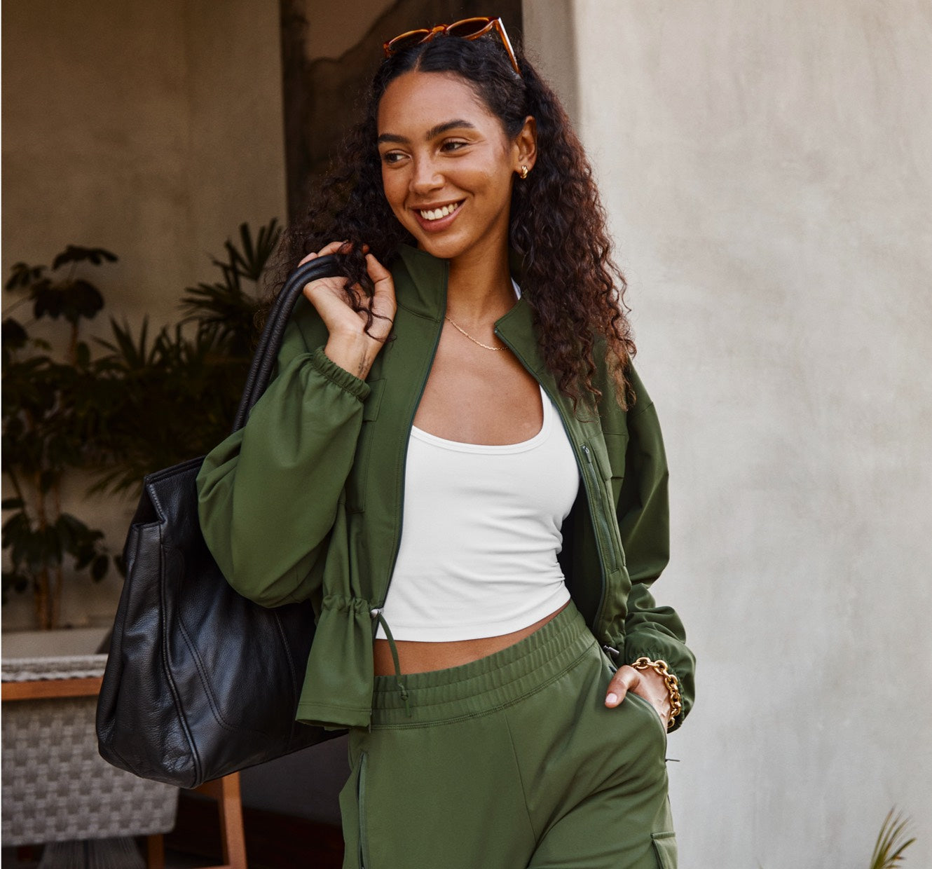 model is wearing a green zip-up cargo style jacket and green cargo style pants. 
