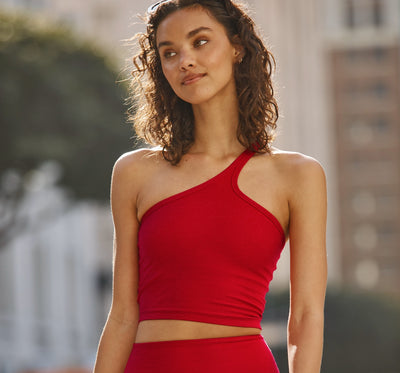 model is wearing a red one-shoulder crop tank.