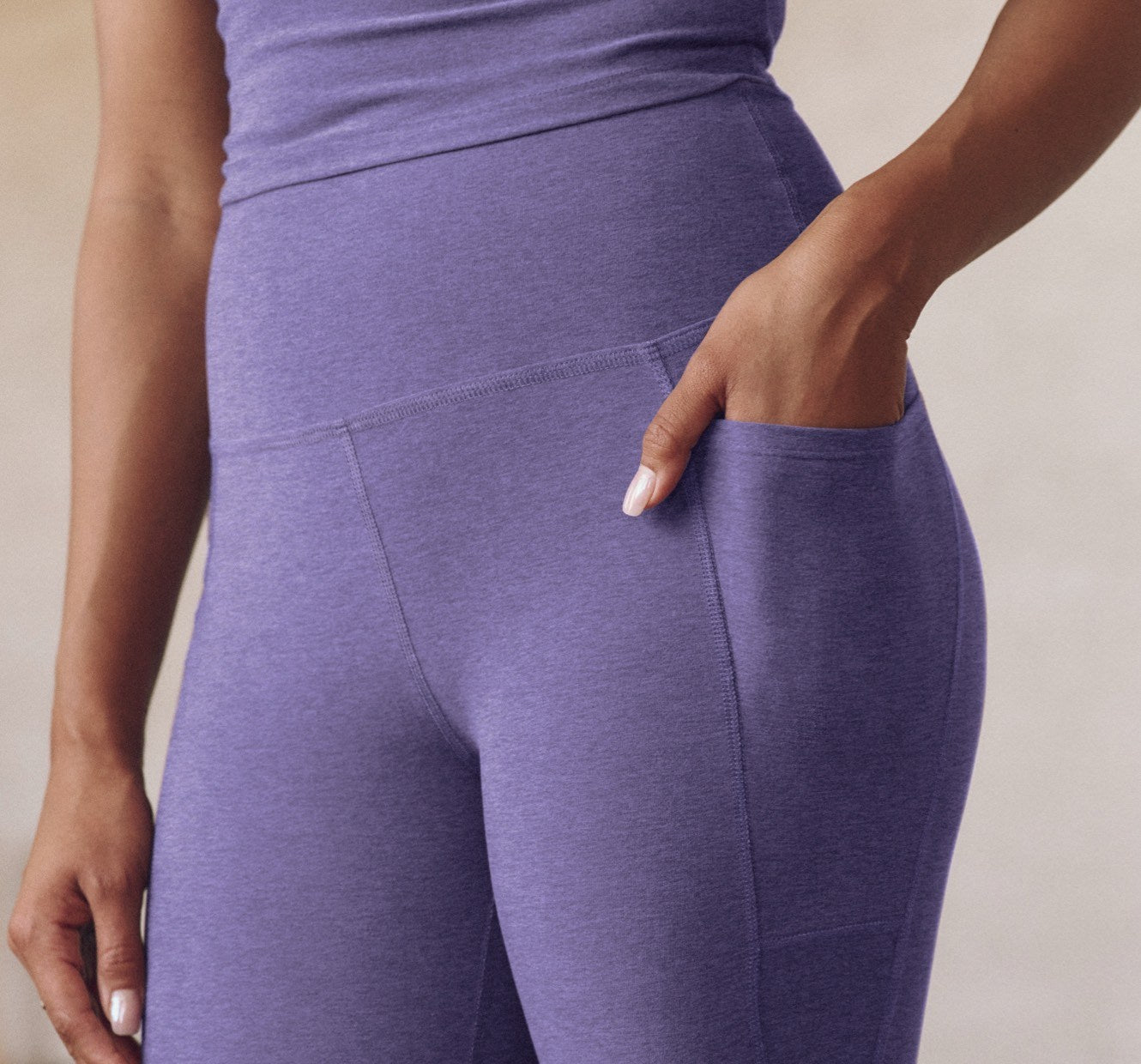 model is wearing purple high-waisted midi leggings with pockets. 