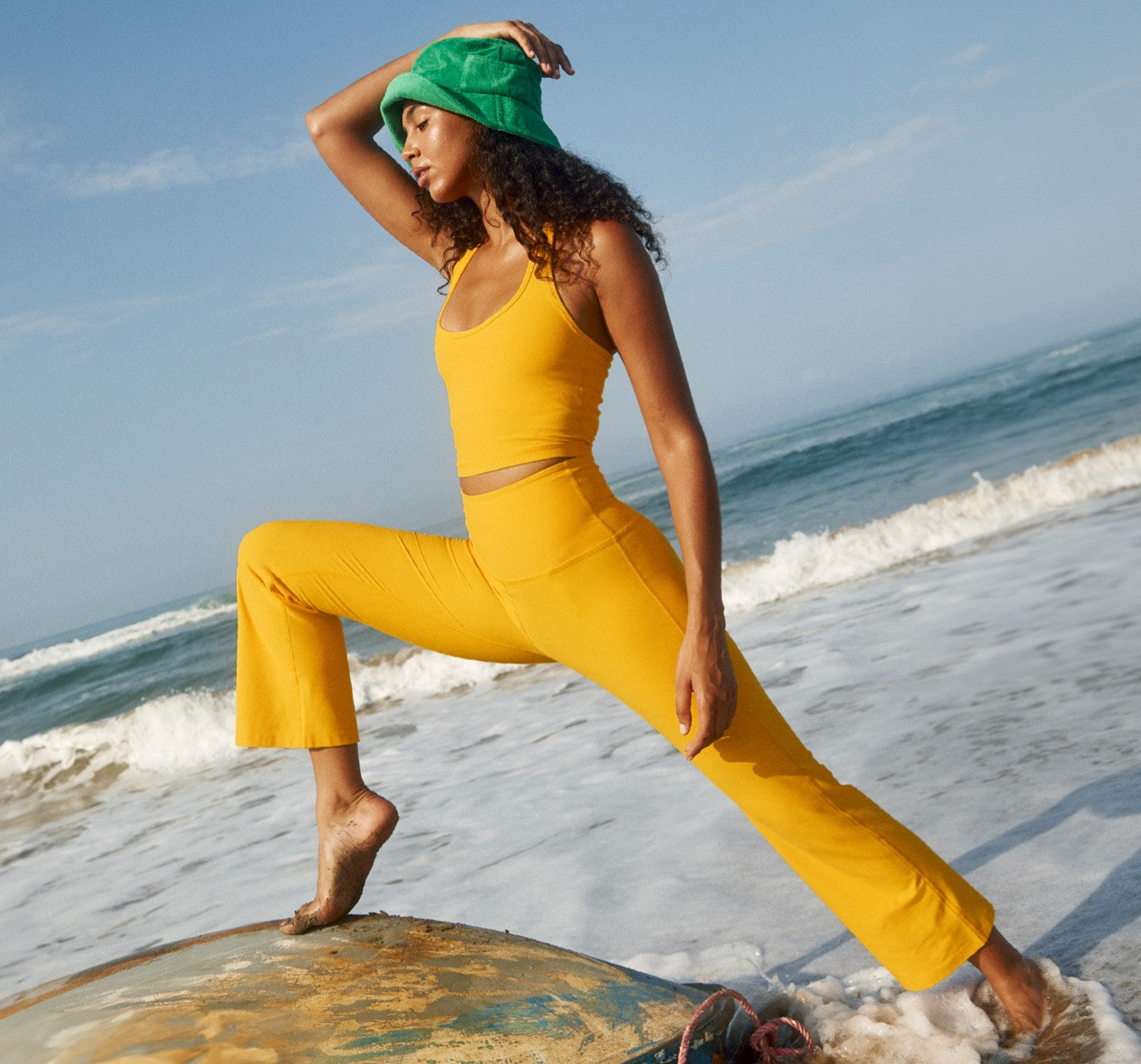 model is wearing a yellow halter cropped tank and yellow cropped pants. 
