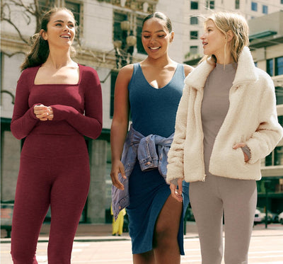 model on the left is wearing a red long sleeve square neck top and red high-waisted midi leggings. model in the middle is wearing a blue midi dress with a front side slit. model on the right is wearing a brown mock neck long sleeve cropped shirt and brown high-waisted midi leggings with a white sherpa zip-up jacket.