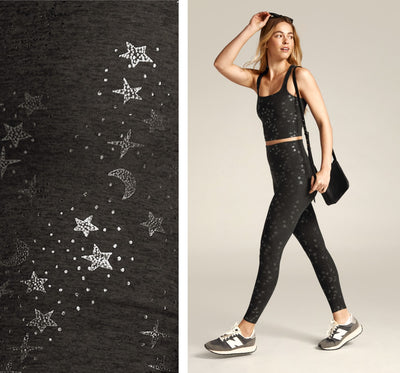 model is wearing a black square neck cropped tank with a star print and black high-waisted midi leggings with a star print. 