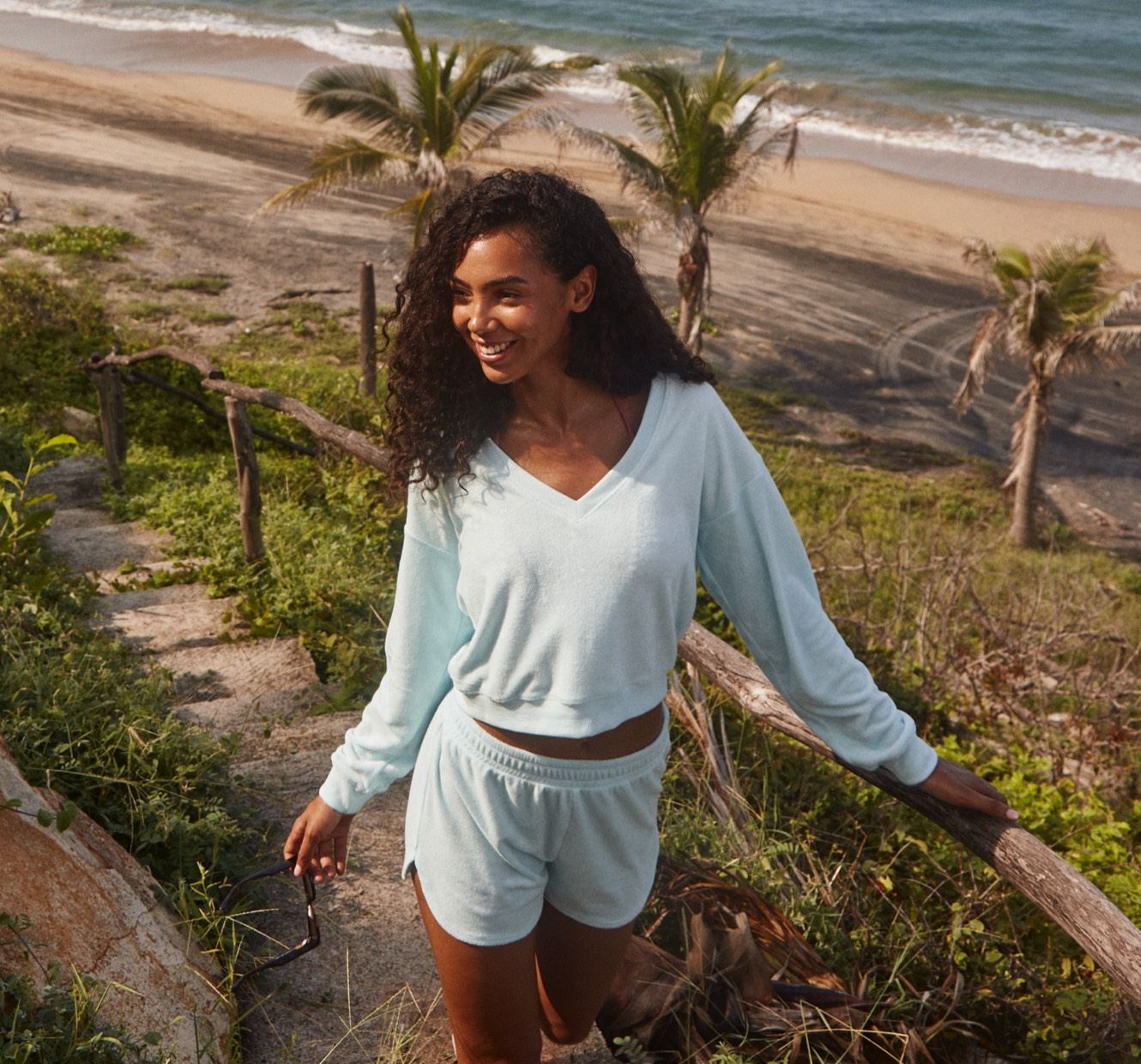 model is wearing a blue terry fabric v-neck long sleeve and blue terry fabric shorts. 