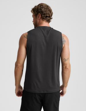 Man wearing a black sleeveless shirt and shorts on a light gray background. 