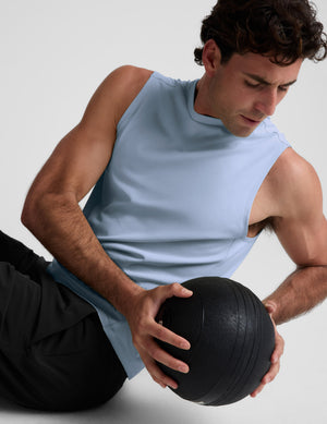 Man wearing a blue tank and black shorts against a plain background. 