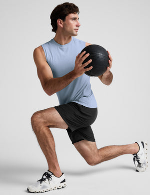 Man wearing a blue tank and black shorts against a plain background. 