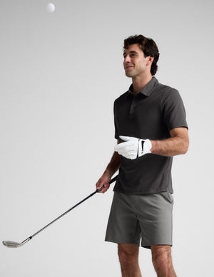 Man wearing a dark gray polo shirt against a light gray background. 