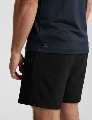Person wearing blue shorts and a dark shirt on a light gray background. 