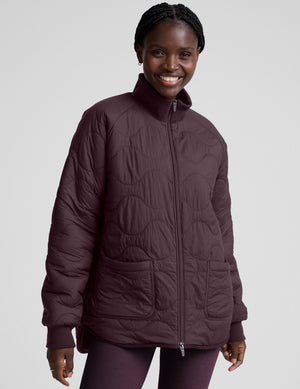 woman wearing a purple quilted jacket against a plain background. 