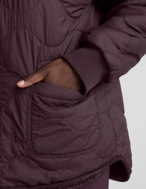 woman wearing a purple quilted jacket against a plain background. 