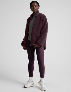woman wearing a purple quilted jacket against a plain background. 