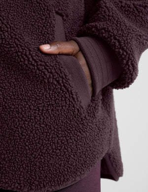 woman wearing a purple quilted jacket against a plain background. 