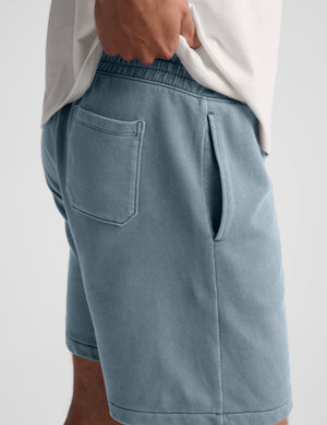Man wearing Blue Beach Washed Terry Men's Short with a white t-shirt, showing side slant and back patch pocket details.