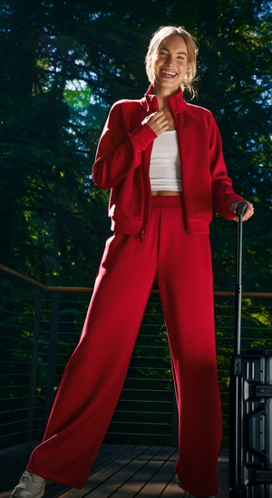 Person wearing a red tracksuit standing outdoors with trees in the background. 