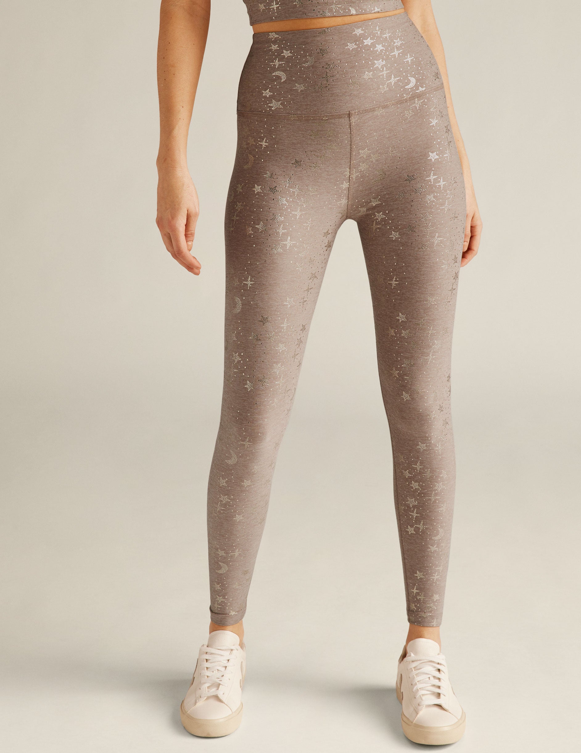 beige high-waisted midi leggings with a golden star printed detailing. 