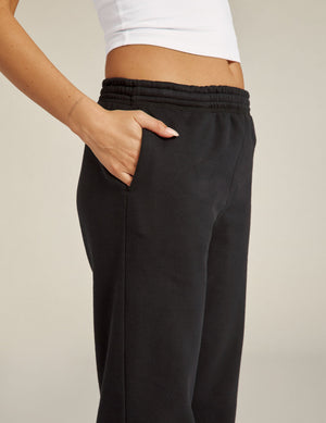 A person wears the black On the Go Jogger with a hand in the side pocket, featuring an elastic waistband and relaxed fit.
