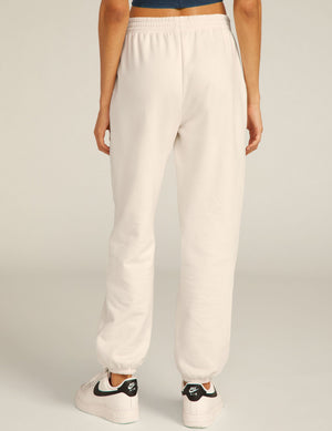 Back view of the cream On the Go Jogger featuring a relaxed fit, elastic waistband, and gathered cuffs at the ankles.