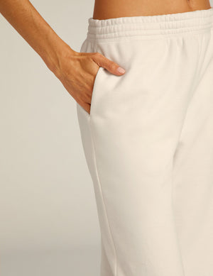 Close-up of On the Go Jogger in cream featuring an elastic waistband and side seam pocket with a hand tucked inside.