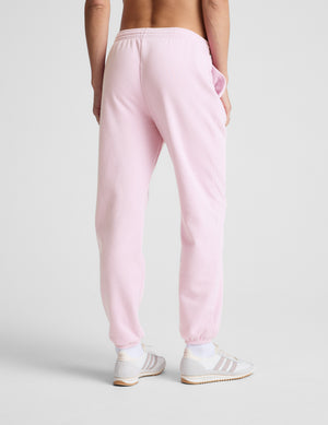 Person wearing pink sweatpants and white sneakers on a light gray background.