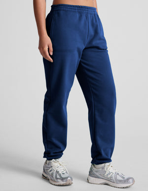 model wearing a blue cropped racerback tank and fleece joggers with pockets on a light gray background.