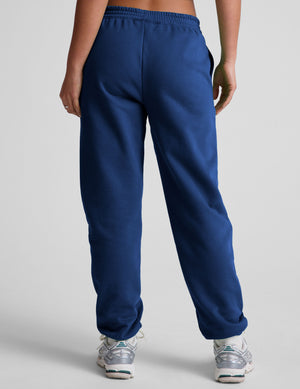 model wearing a blue cropped racerback tank and fleece joggers with pockets on a light gray background.