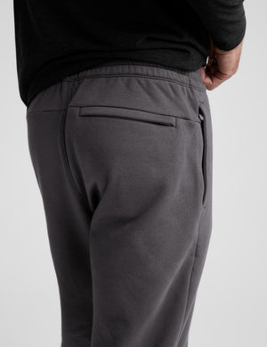 Person wearing dark gray sweatpants on a white background. 
