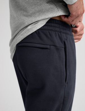 Close-up of dark Classic Fleece Men's Jogger showing the elastic waistband, side zipper pocket, and horizontal welt pocket.
