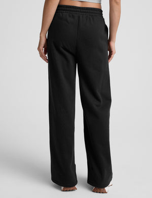model wearing a gray tank top and black wide-leg pants on a plain background. 