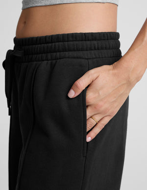 model wearing a gray tank top and black wide-leg pants on a plain background. 