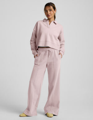 Woman wearing a pink fleece collared sweatshirt and pink fleece pintuck pants against a plain background. 