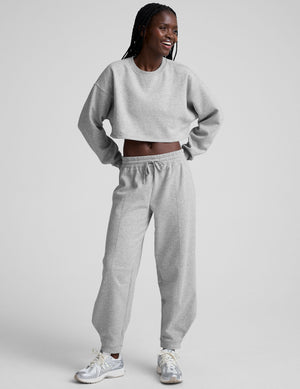 model is wearing gray fleece barrel style sweatpants against a plain background. 