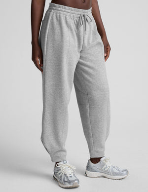 model is wearing gray fleece barrel style sweatpants against a plain background. 