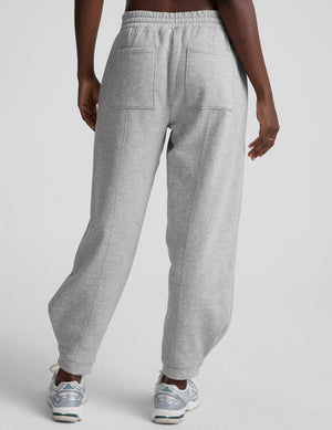 model is wearing gray fleece barrel style sweatpants against a plain background. 