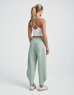 model wearing a white cropped tank and blue barrel style sweatpants against a plain background. 