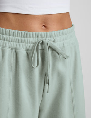 Person wearing a light blue sweatshirt and barrel sweatpants set on a plain background. 