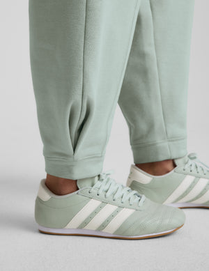 Person wearing a light blue sweatshirt and barrel sweatpants set on a plain background. 