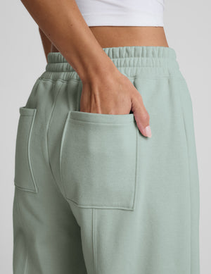 Person wearing a light blue sweatshirt and barrel sweatpants set on a plain background. 