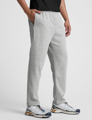 man wearing a gray straight leg fleece sweatpants on a plain background. 