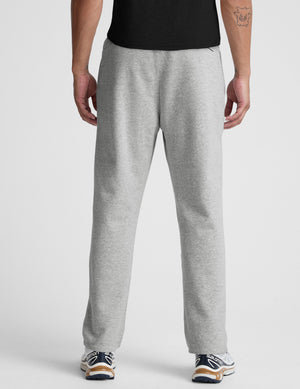 man wearing a gray straight leg fleece sweatpants on a plain background. 
